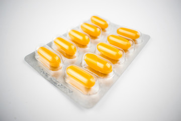 Yellow pills in a blister on a white background.