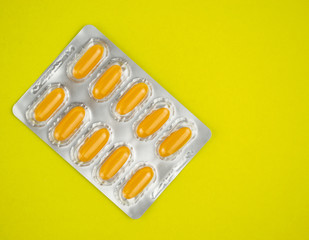 Yellow pills in a blister on a yellow background.