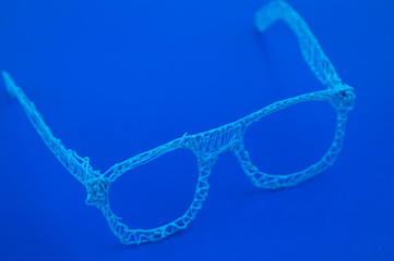 Glasses made with a 3d pen on a blue background.