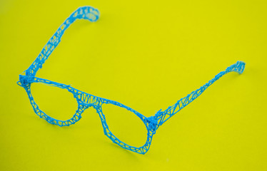 Glasses made with a 3d pen on a yellow background.