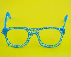 Glasses made with a 3d pen on a yellow background.