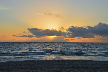 colorful sunset over the Atlantic Ocean, beach, coastline, waves. the light of the sun making its...