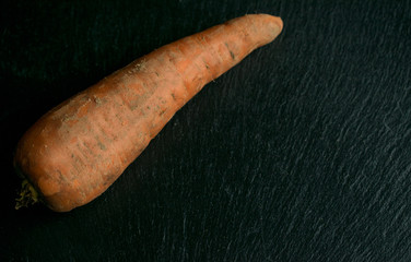 Unwashed carrots on a black background.
