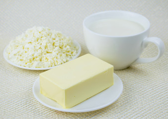 A set of dairy products: milk, cottage cheese, butter on a light background.
