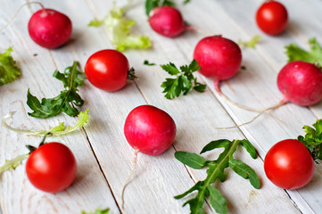 Tomatoes, garden radish, lettuce leaves, arugula, fennel and parsley on a wooden background