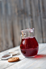 Jug with drink, cookies and a bouquet of flowers in a vase on a wooden background