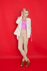 Stylish blonde woman on red background in autumn clothing