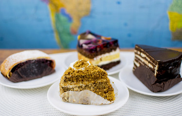 Four different cakes on white plates.