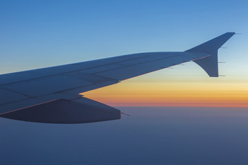 Fototapeta premium Wing of an airplane in the sunset. Airplane wing out of window.
