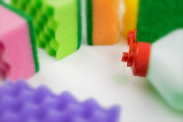 Multicolored foam rubber sponges and detergent on a light background.