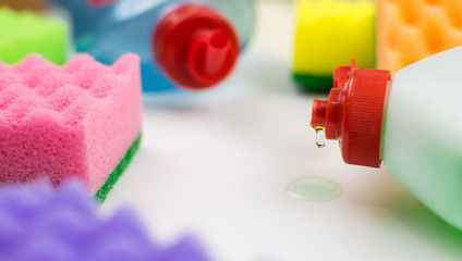 Multicolored foam rubber sponges and detergent on a light background.