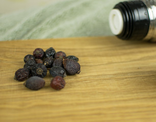 Berries of a dogrose and a thermos on a wooden background.
