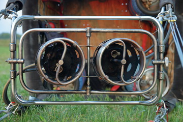 Palniki do ogrzewania balonu gazem, z bilska, od przodu, leżą na trawie, za nimi na boku leży duży balonowy kosz, widać jego dno, butle z gazem © Wioletta