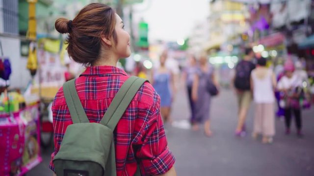 Traveler backpacker asian woman travel in Khao San road at Bangkok, Thailand. Happy young female spending holiday trip at amazing landmark and enjoy her journey in traditional city.