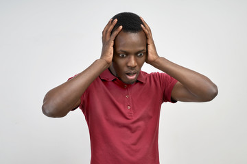 Indoor short stunned young African-American student looking down with a surprised expression. 