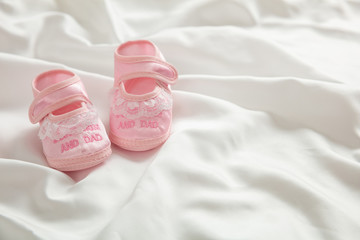 Baby girl shoes  on white satin, copy space