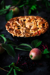 Pie with apples and black elderberries .Dark rustic photo
