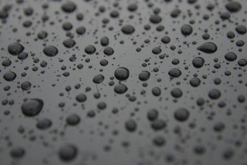 Water rain drops bakground over black surface texture. Beautiful texture of rain drops.