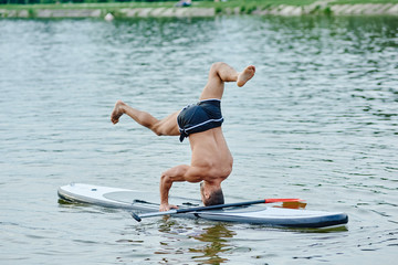 Standing on head, doing yoga exercises, swimming on sup boad in city lake.