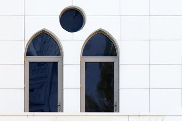 White wall with an arched and round windows, detail of building exterior, urban geometry, copy space.  Abstract minimal style architecture background.