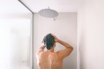 Man taking a shower washing hair with shampoo product under water falling from luxury rain shower head. Morning routine luxury hotel lifestyle guy showering. body care hygiene.