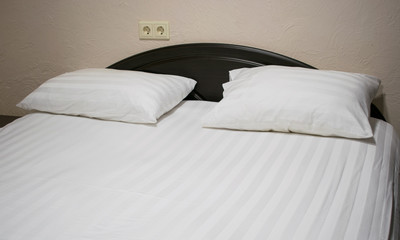 Bed with a white sheet and two pillows.