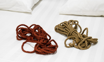 Ropes for shibari on a white bed.