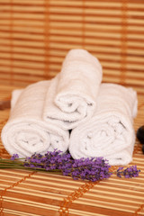 Fototapeta na wymiar White towels and massage rocks in spa salon over dark and light bamboo background