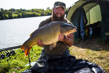 Happy angler with carp fishing trophy