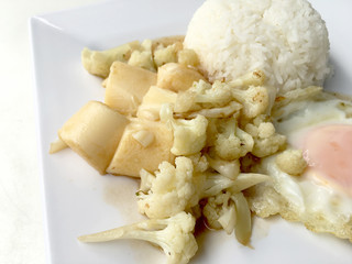 Stir Fried Tofu in Chinese Style,Deep Fried Tofu with Gravy Sauce ,Stir fried tofu with cauliflower and thai style fried egg in white plate on white background. Vegetarian Food, healthy food.