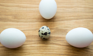 Quail eggs and chicken eggs on a wooden background.