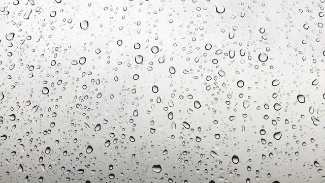 Close up image of raindrops falling on a window.