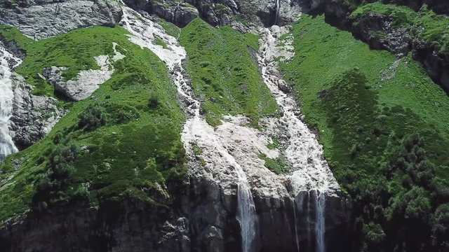 Waterfall flowing down from high mountains on a Sunny day. Top view of the mountain from which the river flows