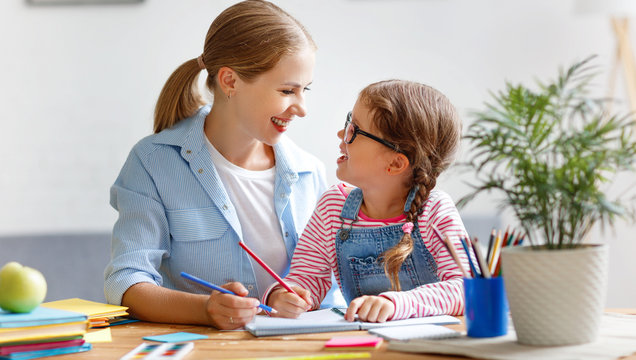 mother and child daughter doing homework writing and reading at home.