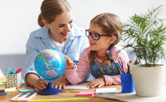 mother and child daughter doing homework geography with globe