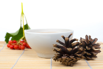viburnum berries, pine cones and tea cup on bamboo table