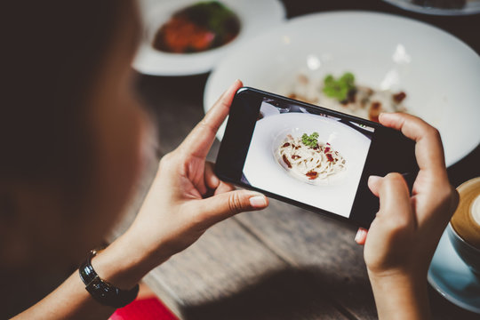 Woman using phone taking photo for food dinner and lunch meal on table