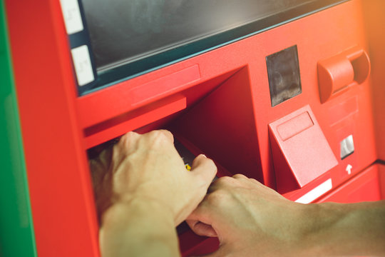 Man hand entering PIN code on ATM machine keypad and cover it with other hand for security.