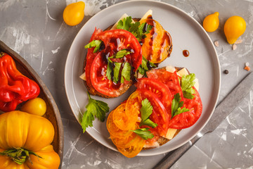 Sandwiches with tomatoes and cheese on gray plate, top view.