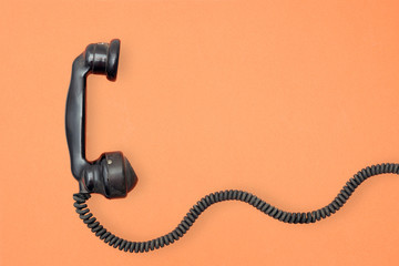 vintage phone hanset with cord on orange background