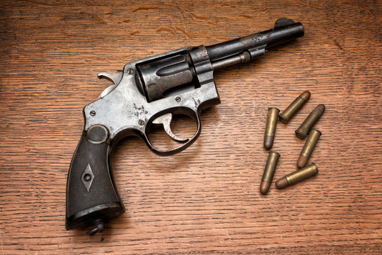 old military police rusty revolver handgun and its six bullets laid on a wooden table