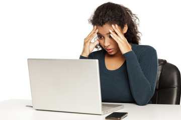Frustrated young african woman at her laptop on white background