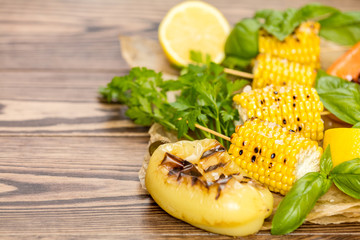 Corn baked in olive oil, with pepper, salt and basil on parchment paper on a dark surface