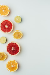 top view of grapefruit, lemon, lime and orange slices, on grey with copy space