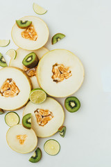 top view of organic melon, lime and kiwi slices, on grey background