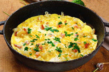 Traditional rustic omelette with bacon, pasta and greens .  Copy space