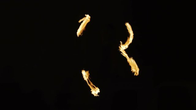 Fire show performance. Abstract strobe effect - fire performer twirling fire at black background . Stop motion effect.
