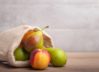 Qtee pears in a bag on a wooden table and a grey background