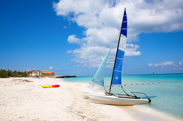 Canoes and catamarans on a sandy beach against the blue sea
