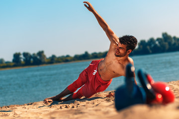 Young man doing fitness workout at a beach on a sunny day.